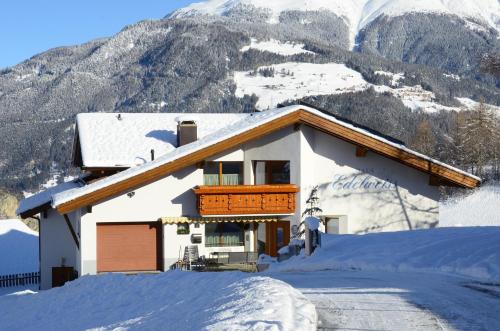 a house in the snow with mountains in the background at EDELWEISS Ladis in Ladis