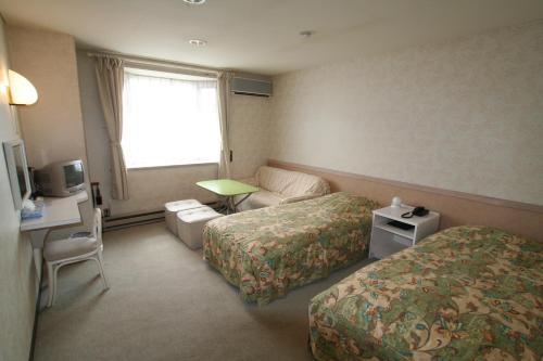 富士河口湖町にあるガストホフ メラージのベッド2台とソファが備わるホテルルームです。