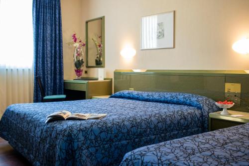 a hotel room with two beds with a book on it at Hotel Royal in Fermo