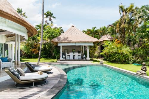a villa with a swimming pool and two lounge chairs at Villa Bliss a paradise of three independent Villas in Canggu