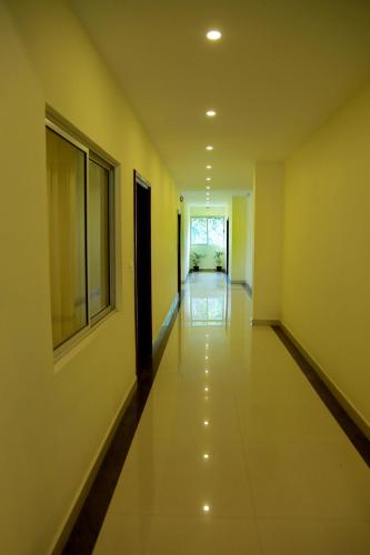 a long hallway with yellow walls and white floors at Woodside residency in Thekkady