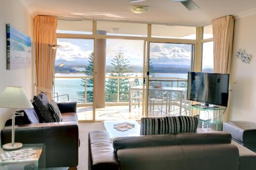 a living room with a couch and a large window at Northpoint Apartments in Port Macquarie