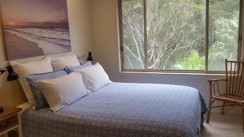 a bedroom with a bed and a large window at Nambucca Beach House in Nambucca Heads