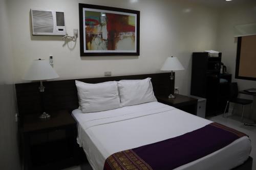 a bedroom with a bed and two lamps and a picture on the wall at Domicilio Lorenzo in Davao City