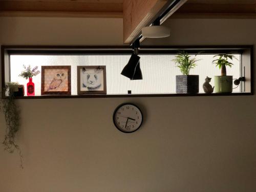 a shelf with plants and a clock on a wall at Stay Nikko Guesthouse in Nikko