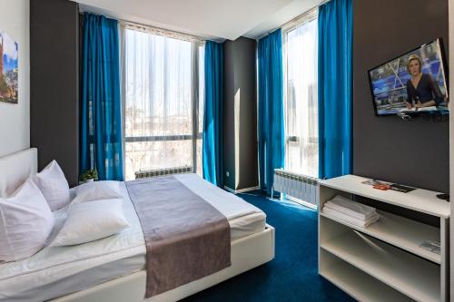 a bedroom with a large bed with blue curtains at Hotel England Tyumen Center in Tyumen