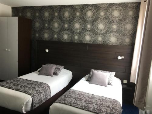 a hotel room with two beds and a wall at The Originals City, Hôtel du Château, Pontivy in Pontivy
