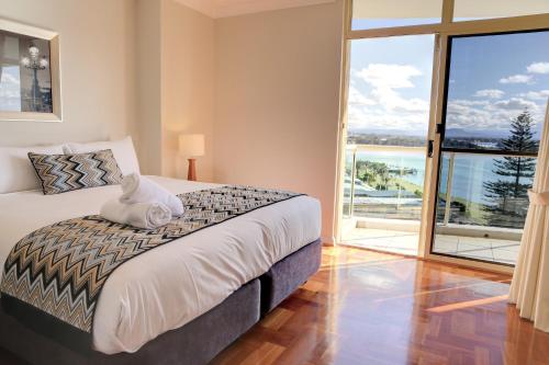 a bedroom with a bed and a large window at Northpoint Apartments in Port Macquarie