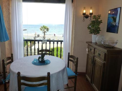 une salle à manger avec une table et une vue sur la plage dans l'établissement Studio les Pieds dans l'Eau, à Six-Fours-les-Plages