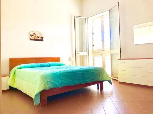 a bedroom with a bed with a blue and green blanket at Appartamenti Sul Mare in Avola