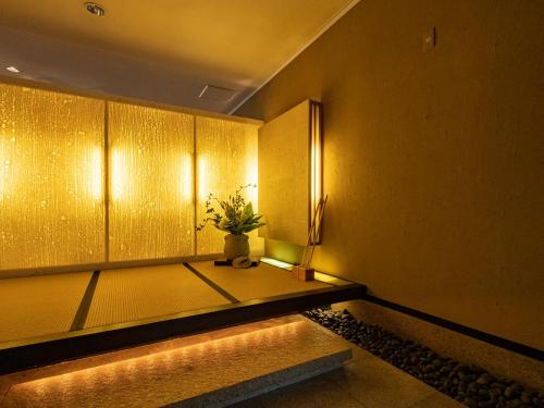 a room with yellow walls and a vase with a plant at Nagominoyado Hanagokoro - Reopening in Mar 2024 in Hakone