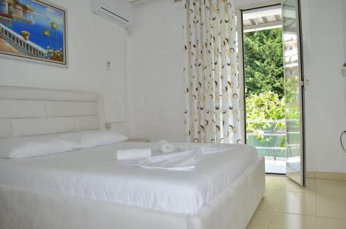 a white bedroom with a bed and a window at Villa Viktor in Sarandë