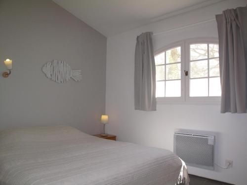 a white bedroom with a bed and a window at Résidence Miro, gîtes climatisés avec piscine et tennis in Les Arcs sur Argens