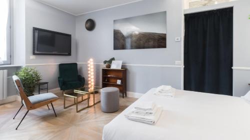 米蘭的住宿－Italianway - Garigliano 4 Flat，一间卧室配有一张床、两把椅子和一台电视