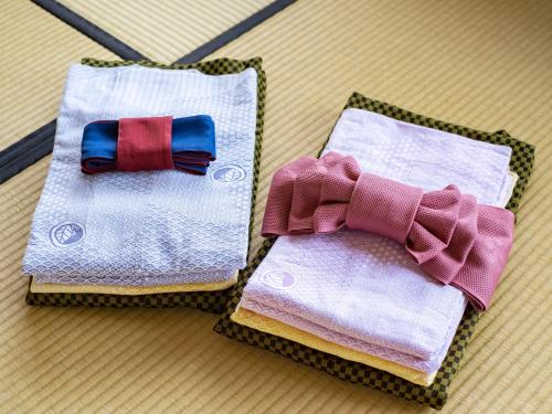two towels with bow ties sitting on a table at Nagominoyado Hanagokoro - Reopening in Mar 2024 in Hakone