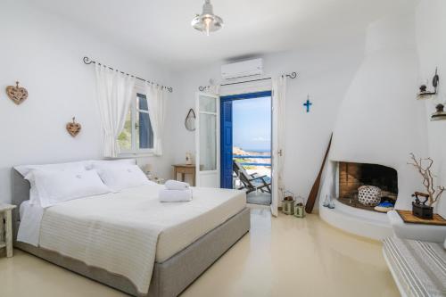 Dormitorio blanco con cama y chimenea en Heavenly Milos suites, en Agia Kiriaki Beach