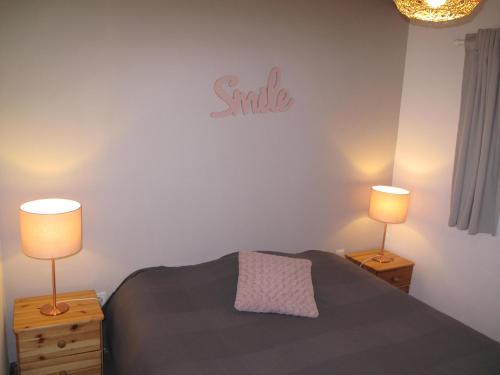 a bedroom with a bed with two lamps and a smile sign at Résidence Miro, gîtes climatisés avec piscine et tennis in Les Arcs sur Argens