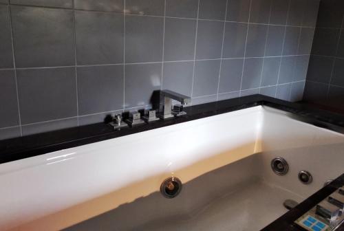 La salle de bains est pourvue d'une baignoire avec un mur carrelé noir et blanc. dans l'établissement Cefalicchio B&B, à Canosa di Puglia