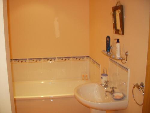 a bathroom with a sink and a bath tub at Beech House in Portballintrae