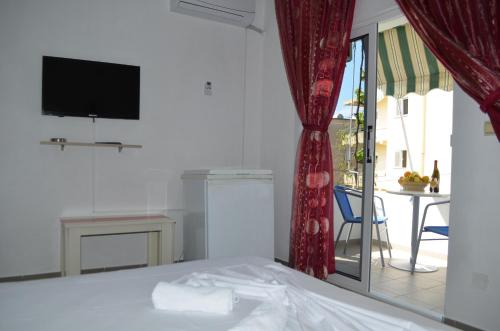 a bedroom with a bed with a television and a balcony at Villa Viktor in Sarandë