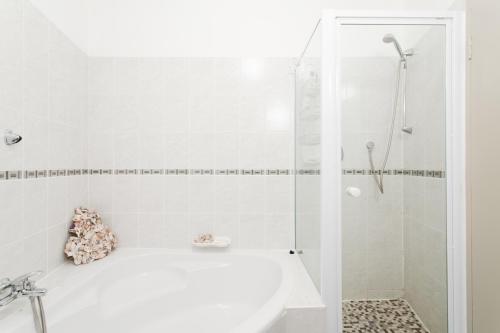 un bagno bianco con vasca e doccia di Breathtaking views, brand new renovated apartment a Città del Capo