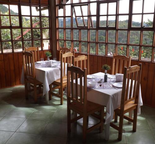 jadalnia ze stołami, krzesłami i oknami w obiekcie Pousada AlpenRose w mieście Campos do Jordão