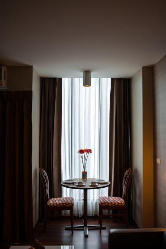 a table with two chairs and a vase of flowers on it at Marsi Hotel Bangkok in Bangkok