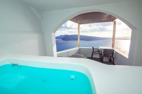 a bath tub in a room with a view of the ocean at Theodora Suites in Oia
