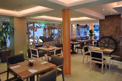 a restaurant with wooden tables and chairs and a pillar at Nelia Gardens in Ayia Napa