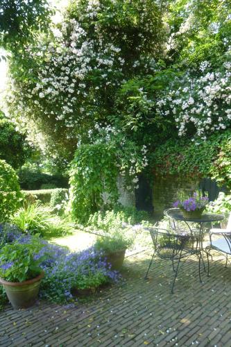 a garden with a table and chairs and flowers at Guesthouse Veerhoeve in Sluis
