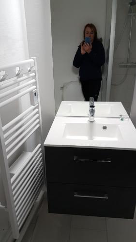 une femme prenant une photo d'un lavabo dans une salle de bains dans l'établissement Kiruna, à Le Mont-Dore