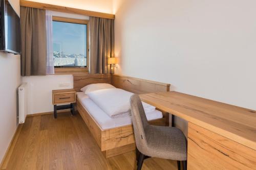 a room with a bed and a desk with a chair at Hotel Hochfilzer in Ellmau