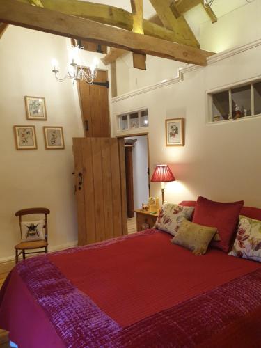 a bedroom with a large bed with a red blanket at The Millers Cottage in Okehampton