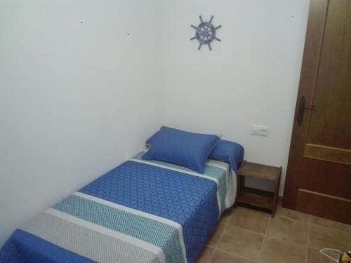 1 dormitorio con 1 cama con sábanas azules y reloj en la pared en Casa 100m2, en Chiclana de la Frontera