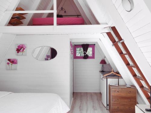 an attic bedroom with a bed and a staircase at La Rossignolerie - Cabane aux oiseaux in Chouzy-sur-Cisse