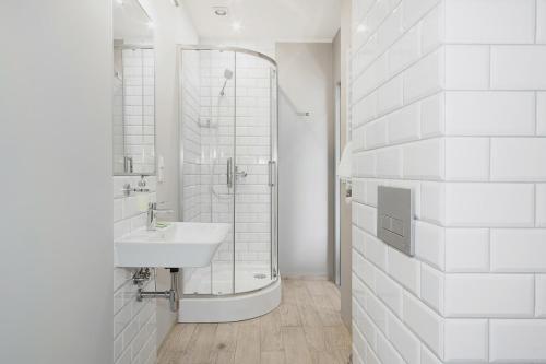 La salle de bains blanche est pourvue d'un lavabo et d'une douche. dans l'établissement Lemon, à Piotrków Trybunalski