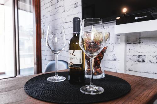 a bottle of wine and two wine glasses on a table at Apartma Remi in Piran