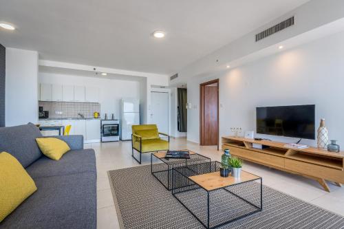 a living room with a couch and a tv at Cosy and sunny apartment in Nevet Tsedek with pool in Tel Aviv