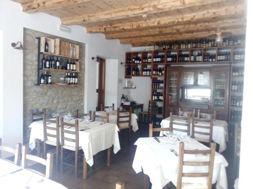 un ristorante con tavoli e sedie bianchi e un muro di pietra di La Foresta Albergo Ristorante Pizzeria a Badia Prataglia