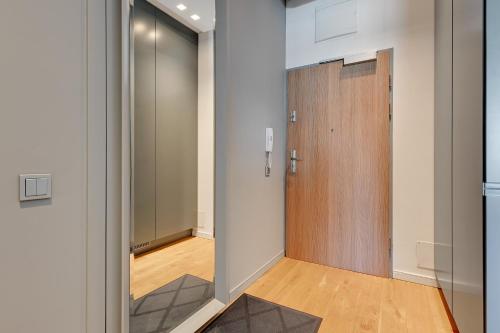 Un pasillo con una puerta de madera en una habitación. en Wave Apartments - Cztery Oceany, en Gdansk