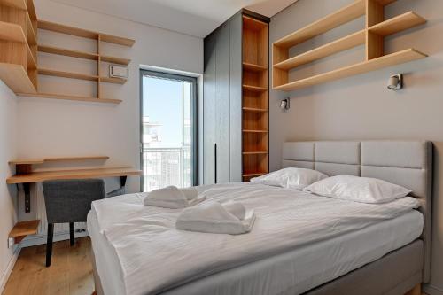 Un dormitorio con una cama y un escritorio y una ventana. en Wave Apartments - Cztery Oceany, en Gdansk