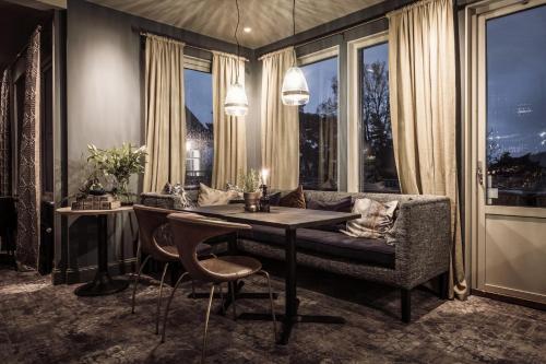 a dining room with a table and a couch and windows at Destination Bokenäset in Uddevalla