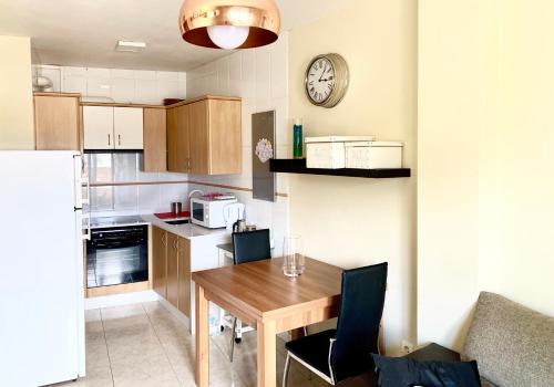 a kitchen with a wooden table and a clock on the wall at Apartamento a 50 m de Playa-Jardín. Boiro in Boiro