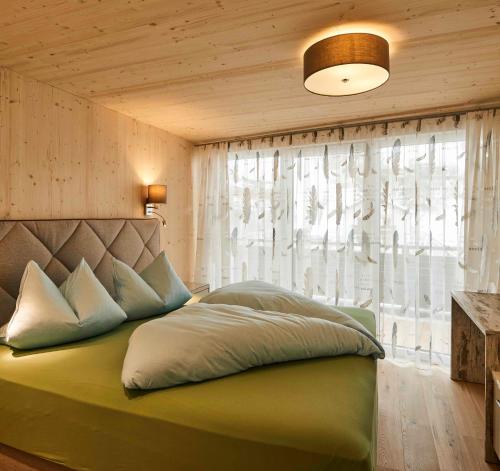 a bedroom with a green bed with a window at Apart Sailer in Ried im Oberinntal