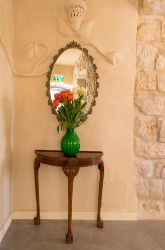 a vase of flowers on a table with a mirror at The Way Inn - Boutique Suites in Safed