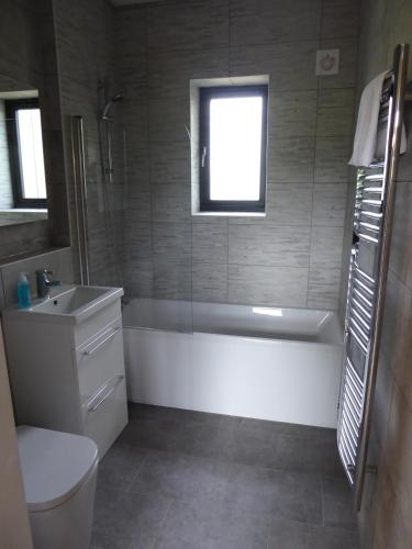 a bathroom with a tub and a toilet and a sink at Auchendennan Farm Self Catering Cottages in Balloch