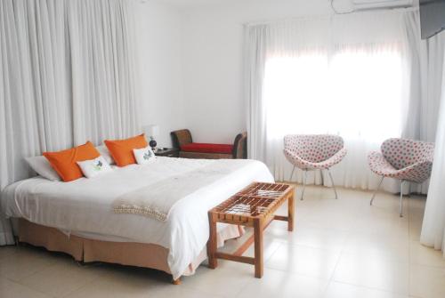 a bedroom with a bed and two chairs and a window at El Pueblito Iguazú in Puerto Iguazú