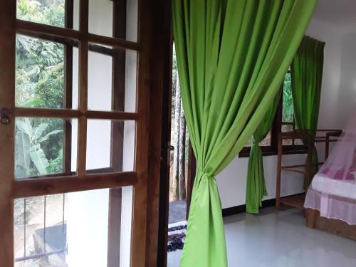 an open door to a bedroom with green curtains at Nine Arch Araliya Homestay in Ella