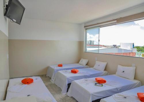 a room with three beds with orange pillows on them at Hotel Cco Goiânia in Goiânia