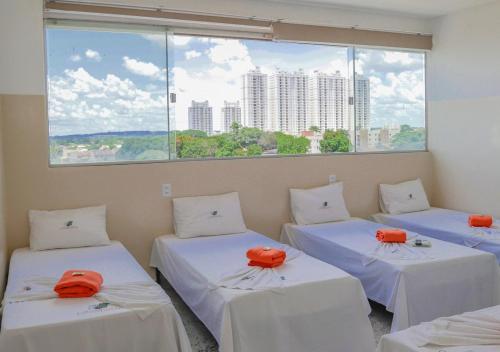 three beds in a room with a large window at Hotel Cco Goiânia in Goiânia
